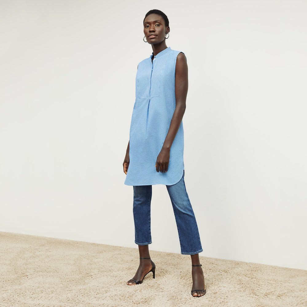 Front image of a woman standing wearing the gigi dress in gingham seersucker in capri blue and white