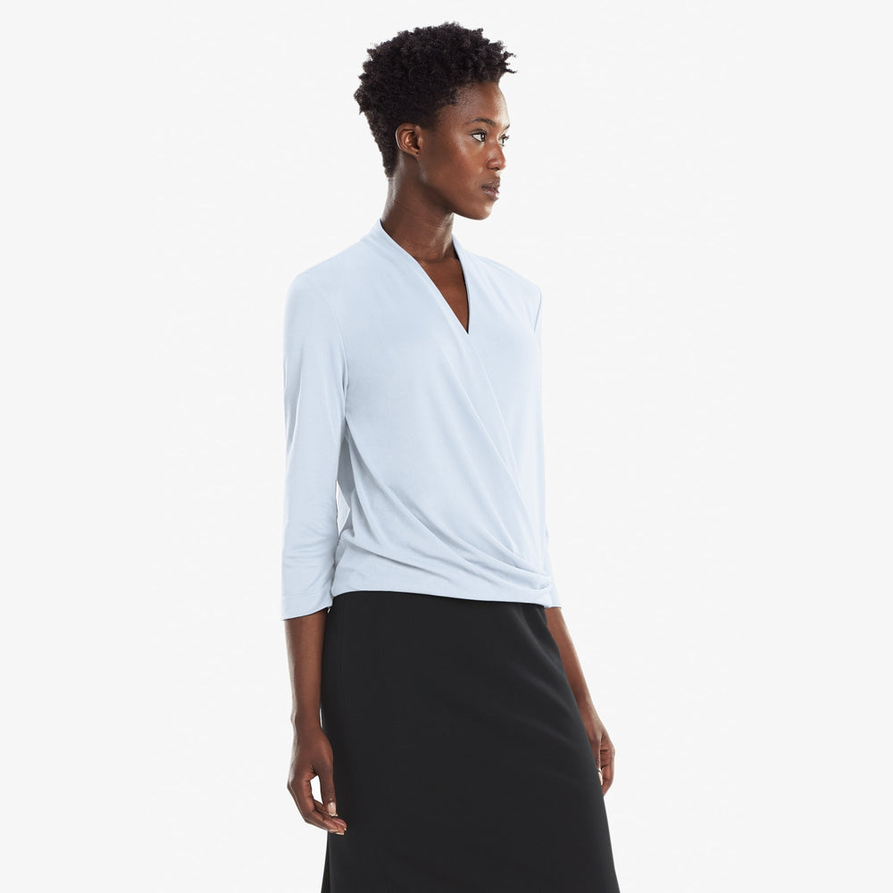 Side image of a woman standing wearing the Deneuve top in Oxford Blue