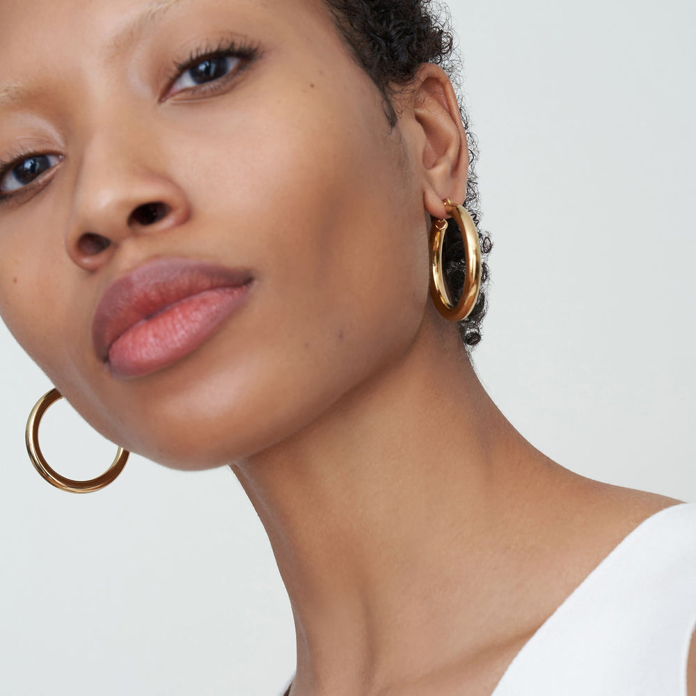 Detail image of a woman standing wearing the Claressa Earrings—Medium in Gold