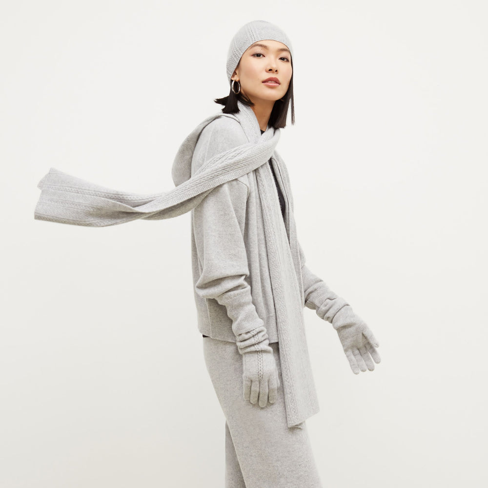 Side image of a woman standing wearing the Circle Cable Scarf—Cashmere in Heather Gray
