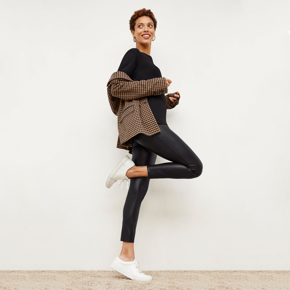 Side image of a woman standing wearing the Harrington Leather—Vegan Leather in Black